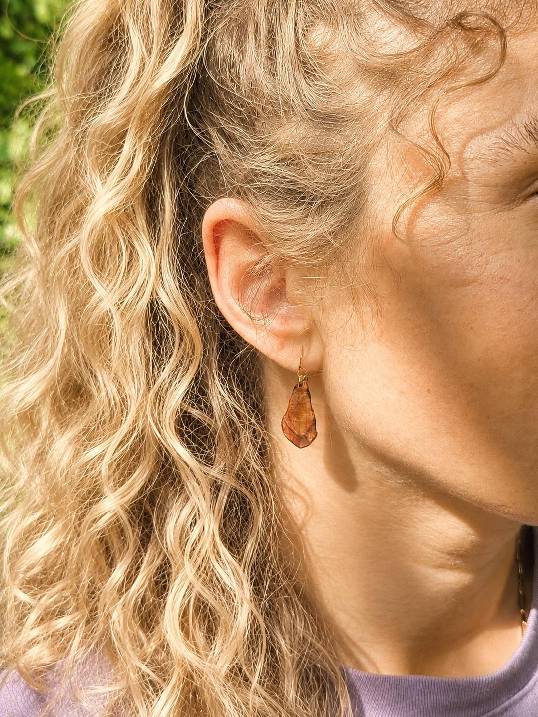 Ein bernsteinfarbener Ohrring, getragen zu blonden Locken
