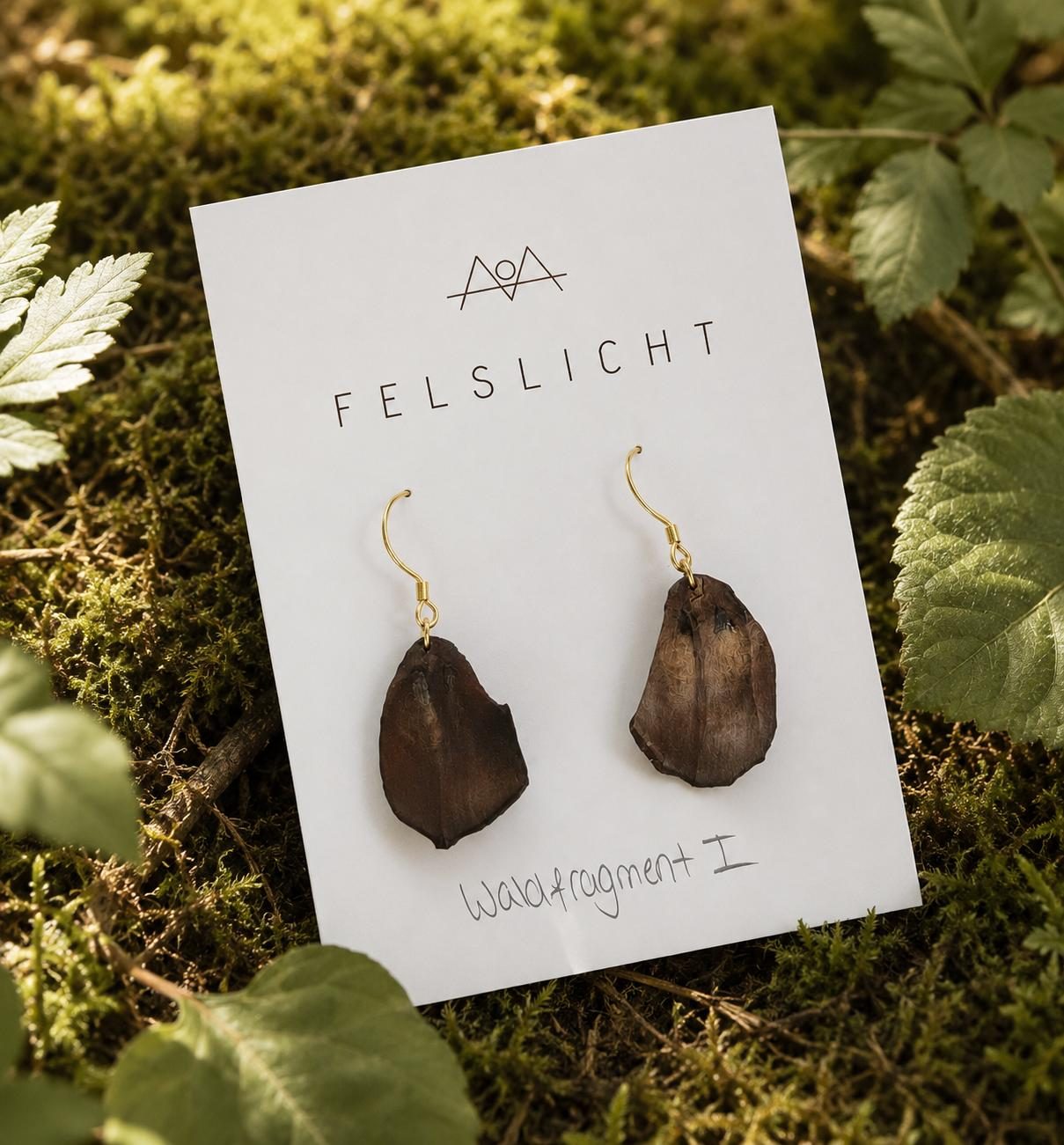 Ein Paar Ohrringe auf einer FELSLICHT Karte mit dem Namen Waldfragment I, auf Moos